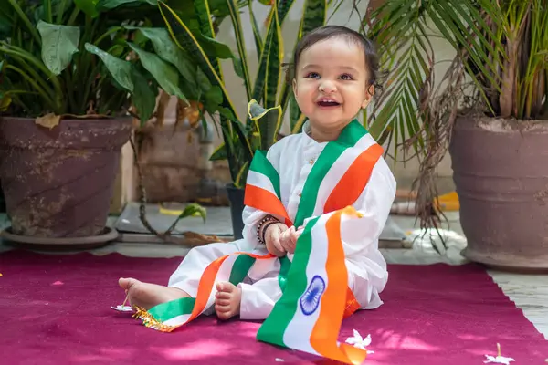 在传统布上挂着印第安三色旗的可爱幼儿 面部表情纯真 免版税图库图片