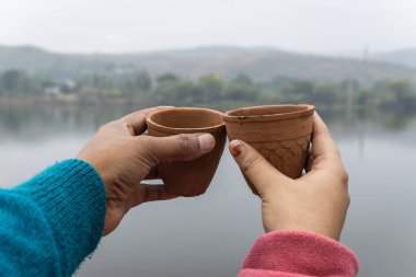 Geleneksel çömlek kil bardakta servis edilen sıcak çayın tadını çıkaran çiftler. Bulanık dağ manzaralı.