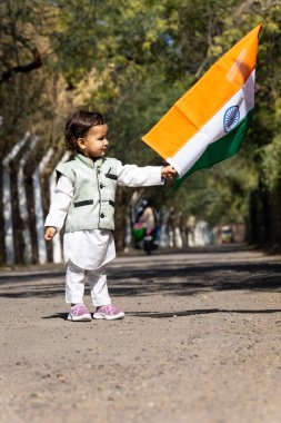 Genç bir çocuk Hindistan 'ın üç renkli bayrağını gün boyu düz açıyla sallıyor.