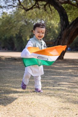 Hindistan ulusal bayrağıyla gezen sevimli Hintli çocuk sabah geleneksel elbisesiyle dışarıda yürüyor.