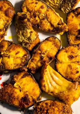 Kızarmış balık evde farklı açılardan beyaz kapta tutulur.