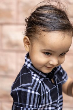 Siyah tişörtlü şirin bir çocuk. Farklı açılardan dışarı ateş ediyor.