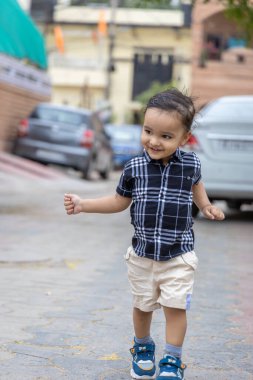 Siyah tişörtlü şirin bir çocuk sokakta farklı açılardan yürüyor.