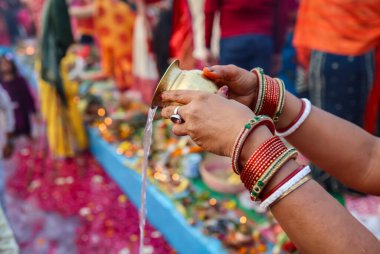 holy water offerings by indian devotee doing traditional rituals at chhath festival at morning clipart