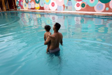 Baba ve oğul akşam havuz banyosunun keyfini çıkarıyorlar.