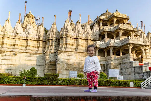 stock image cute kid with ancient unique temple architecture with bright blue sky background at day image is taken at ranakpur jain temple rajasthan india.