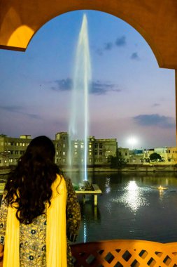 Kız uzun suyla akan çeşmeyi seyrediyor Akşamları dramatik bir gökyüzü ile