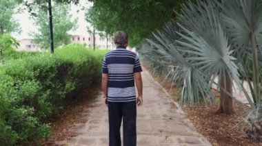 Yalnız başına, hasta bir adam akşam vakti parka farklı açılardan giriyor.