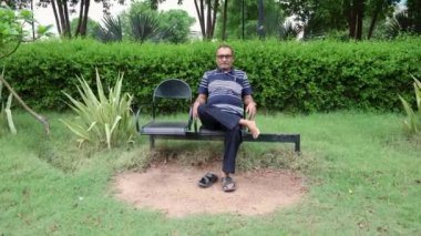 soyutlanmış bir adam akşam düz açıyla park sandalyesinde eğleniyor.