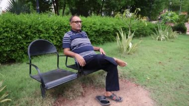 Yalnız bir adam akşamları düz açıyla park sandalyesinde oturuyor.