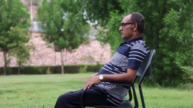 Yalnız bir adam akşamları düz açıyla park sandalyesinde oturuyor.
