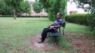 Yalnız bir adam akşamları düz açıyla park sandalyesinde oturuyor.