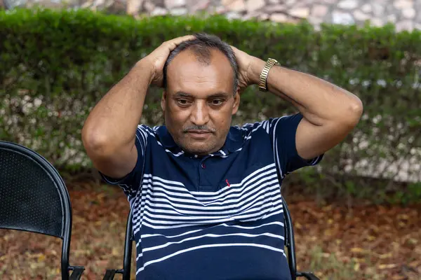 stock image isolated alone man in depression sitting at outdoor park at evening from flat angle