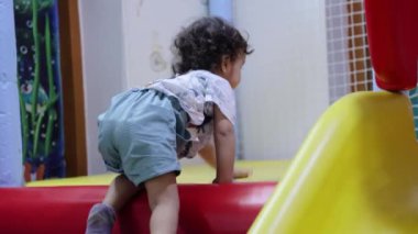 Şirin Hintli bebek, içeride çocuklara sürünüyor. Düz açıdan oynuyorlar.