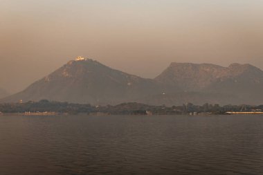 Udaipur Rajasthan Hindistan 'da, el değmemiş sakin gölü olan sisli dağlar sabah görüntüsü alınır..