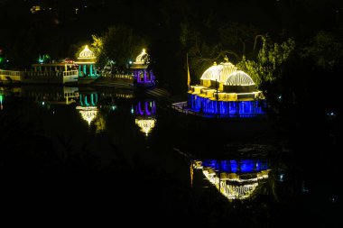 Udaipur Rajasthan Hindistan 'da gece görüntüsünde feribot renkli ışıklar ve su yansıması ile dekore edilmiş tarihi mimari çekilir..
