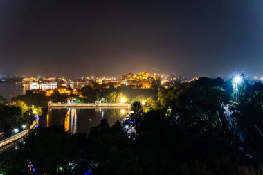 Udaipur Rajasthan Hindistan 'da eşsiz bir perspektiften dramatik ışıklandırmayla gölün gece manzarası çekiliyor..