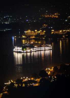 Udaipur Rajasthan Hindistan 'da eşsiz bir perspektiften dramatik ışıklandırmayla gölün gece manzarası çekiliyor..