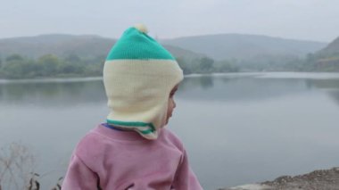 Kışlık elbiseli şirin bebek ve maymun şapkalı masum yüz ifadesi.