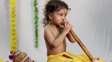 Hindu tanrısı Kirshna gibi giyinmiş, beyaz arka planı olan küçük bir çocuk.