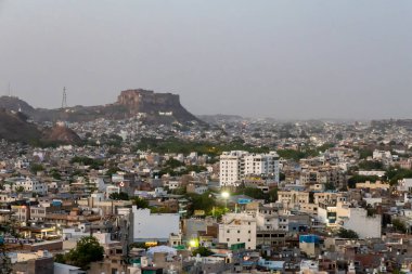 Kalabalık şehir manzaralı beton yoğun evler ve Dusk 'taki Mountain Peak' ten tarihi kale Pachetia Hill Jodhpur Rajasthan 'dan alınmıştır..