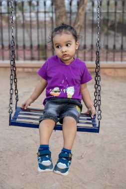 Hintli şirin çocuk eğleniyor Akşam vakti açık hava parkında sallan