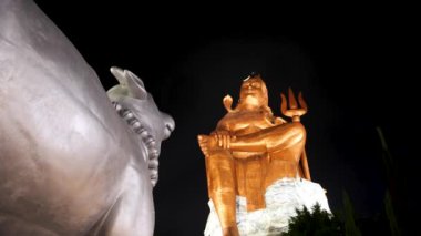 Kutsal Hindu Lord Shiva 'nın izole edilmiş heykeli Meditasyon Duruşu Kutsal boğa ve karanlık gökyüzü ile geceleyin