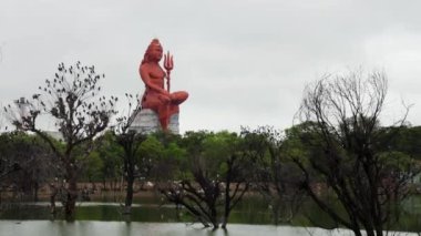 Gün doğumunda Lord Shiva heykelini göl ve kuşlarla meditasyon yaparken.