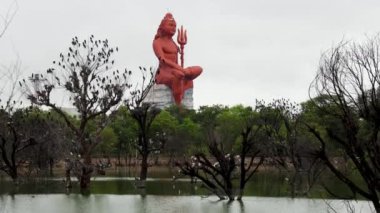 Gün doğumunda Lord Shiva heykelini göl ve kuşlarla meditasyon yaparken.