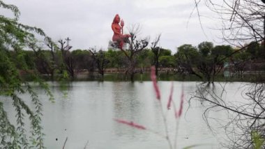 Saf, sakin gölü olan Shiva heykeli ve düz bir açıyla parlak gökyüzü.