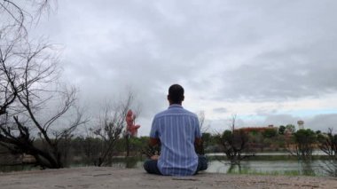 Kutsal Lord Shiva 'nın heykeliyle meditasyon yaparken sabahleyin el değmemiş göl kenarında dramatik bir gökyüzü.