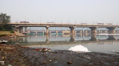 Kirli nehir, endüstriyel ve yerli akışkan maddelerle dolu zehirli köpük ve yol köprüsü sabah videosu yamuna River okhla barrage delhi Hindistan 'da çekiliyor..