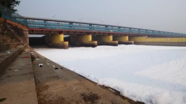 Kirli nehir, endüstriyel ve yerli akışkan maddelerle dolu zehirli köpük ve yol köprüsü sabah videosu yamuna River okhla barrage delhi Hindistan 'da çekiliyor..