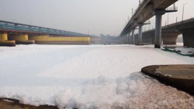 Kirli nehir, endüstriyel ve yerli akışkan maddelerle dolu zehirli köpük ve yol köprüsü sabah videosu yamuna River okhla barrage delhi Hindistan 'da çekiliyor..