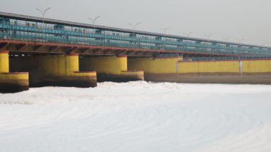 Kirli nehir, endüstriyel ve yerli akışkan maddelerle dolu zehirli köpük ve yol köprüsü sabah videosu yamuna River okhla barrage delhi Hindistan 'da çekiliyor..