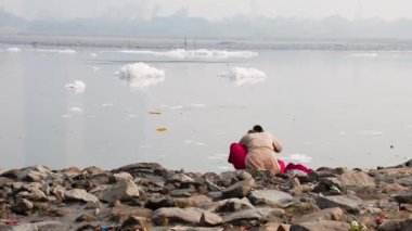 Kirli Nehir 'de sisli bir havada zehirli köpükle yıkanan münzevi kadınlar yamuna Nehri Okhla Barrage Delhi Hindistan' da çekiliyor..