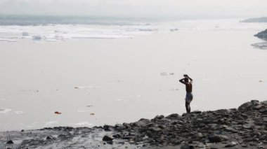 Kirli Nehir 'de sisli bir sabahta zehirli köpükle yıkanan izole bir adam yamuna Nehri Okhla Barrage Delhi Hindistan' da çekiliyor..
