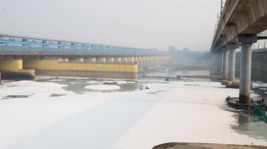 Hız teknesinde kirlenmiş nehir videosunun zehirli köpüğünü seyrelten işçiler Yamuna Nehri Okhla Barrage Delhi Hindistan 'da 4 Kasım 2024 tarihinde çekilmiştir..