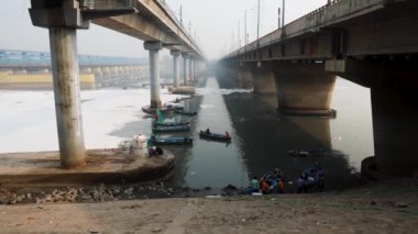 Çağdaş Yol Köprüsü Zehirli Köpük ve İşçi Teknesi ile Kirlenmiş Nehir Bulutlu Sabah Videosu yamuna Nehri Okhla Barrage Delhi Hindistan 'da 4 Kasım 2024' te çekildi..