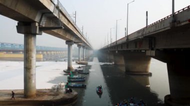 Çağdaş Yol Köprüsü Zehirli Köpük ve İşçi Teknesi ile Kirlenmiş Nehir Bulutlu Sabah Videosu yamuna Nehri Okhla Barrage Delhi Hindistan 'da 4 Kasım 2024' te çekildi..