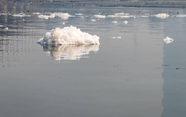 Toxic Foam of industrial and domestic effluents in Contaminated river at morning image is taken at yamuna river okhla barrage delhi india. clipart