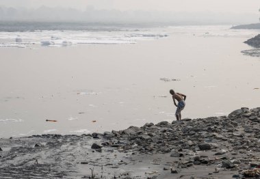 Kirli Nehirde sisli bir şekilde zehirli köpükle yıkanan izole bir adam yamuna Nehri Okhla Barrage Delhi Hindistan 'da sabah görüntüsü alındı..