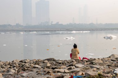 Kirli Nehirde sisli bir köpükle yıkanan yalnız kadınlar yamuna nehrinin okhla baraj ateşi delhi Hindistan 'da sabah görüntüsü alınır..