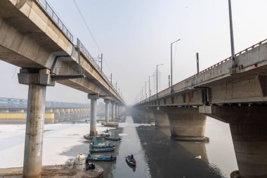 Çağdaş Yol Köprüsü Zehirli Köpük ve İşçi Teknesi ile Kirlenmiş Nehir Bulutlu Sabah Videosu yamuna Nehri Okhla Barrage Delhi Hindistan 'da 4 Kasım 2024' te çekildi..