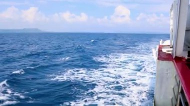 Huzurlu deniz ufku, parlak mavi gökyüzünün altında deniz suyunu kesen gemi suları.