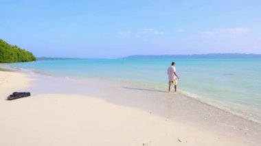 İzole edilmiş bir adam, Andaman ve Nicobar Adaları 'ndaki Havelock Adası' ndaki Radhanagar Sahili 'nde çekilen düz açılı videodan sabah beyaz kumsaldaki el değmemiş deniz dalgalarının keyfini çıkarıyor..