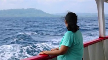 İzole edilmiş bir kız, gün ışığında gemi gözlem galerisinden sakin deniz manzarasının keyfini çıkarıyor.