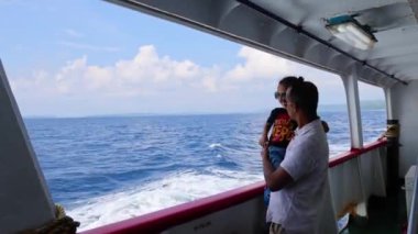 Baba ve oğul, gün ışığında gemi gözlem galerisinden sakin deniz manzarasının keyfini çıkarıyorlar.