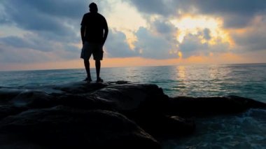 Kala Pathar Sahili 'nde Andaman ve Nicobar Adaları' nda izole edilmiş genç adam dramatik bir gündoğumu ile deniz ufkuna bakıyor..