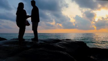 Kala Pathar Sahili Andaman ve Nicobar Adaları 'nda deniz ufku ve dramatik gündoğumu olan gökyüzü videosu çekilen evli çift görülüyor..